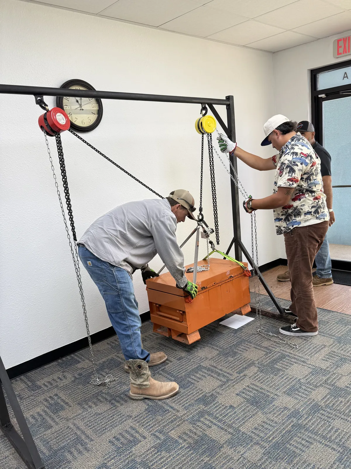 Two students communicating with each other to drift a load across a gantry with chain hoists
