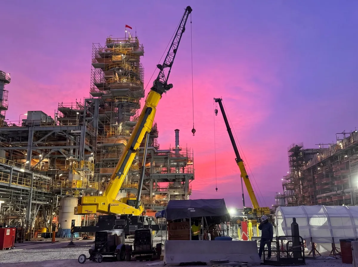 Two mobile cranes rigging at a Coastal Bend refinery turnaround at sunset