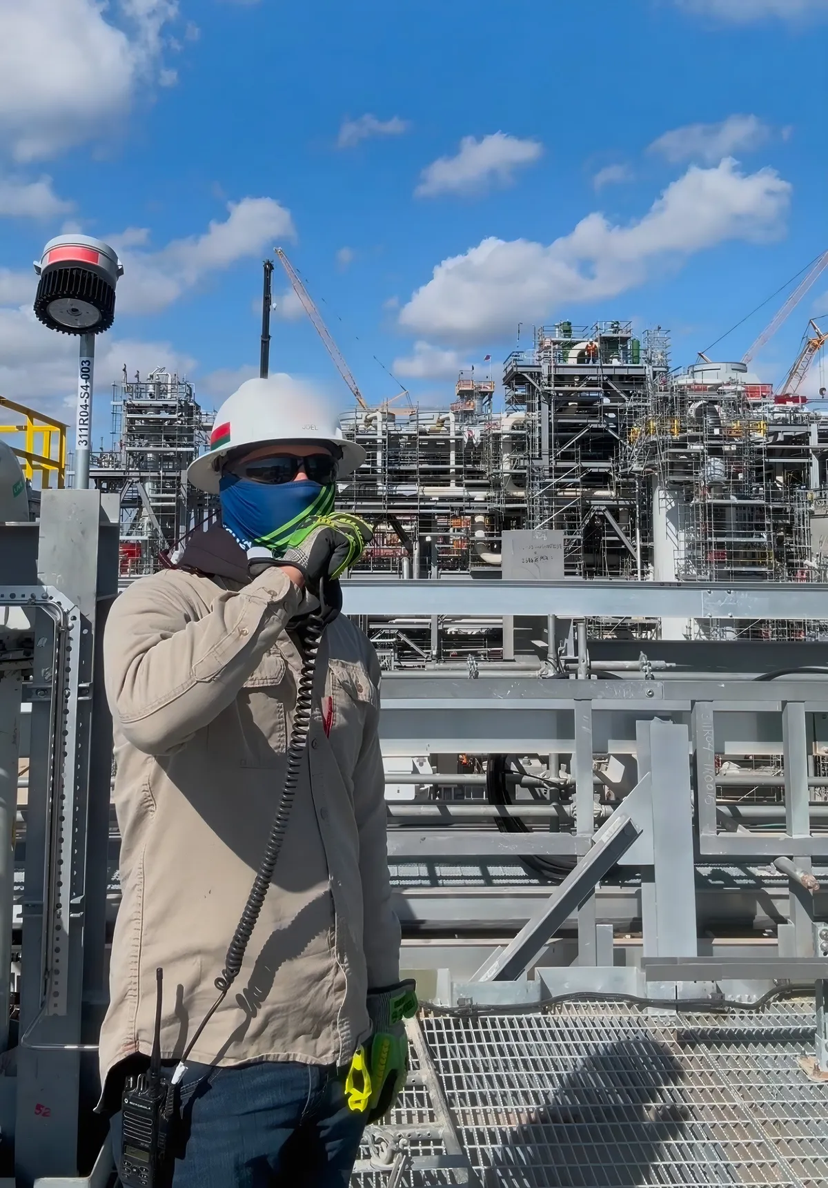 Signal person on the radio from an elevated platform at a refinery jobsite