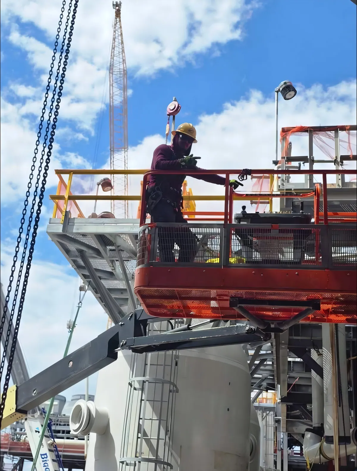 Andres Herrera working from a personnel platform on a refinery lift